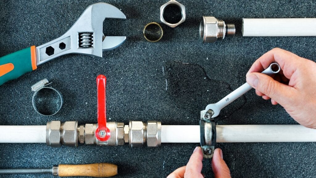 Plumber repairing a pipe valve with an adjustable wrench in Oviedo