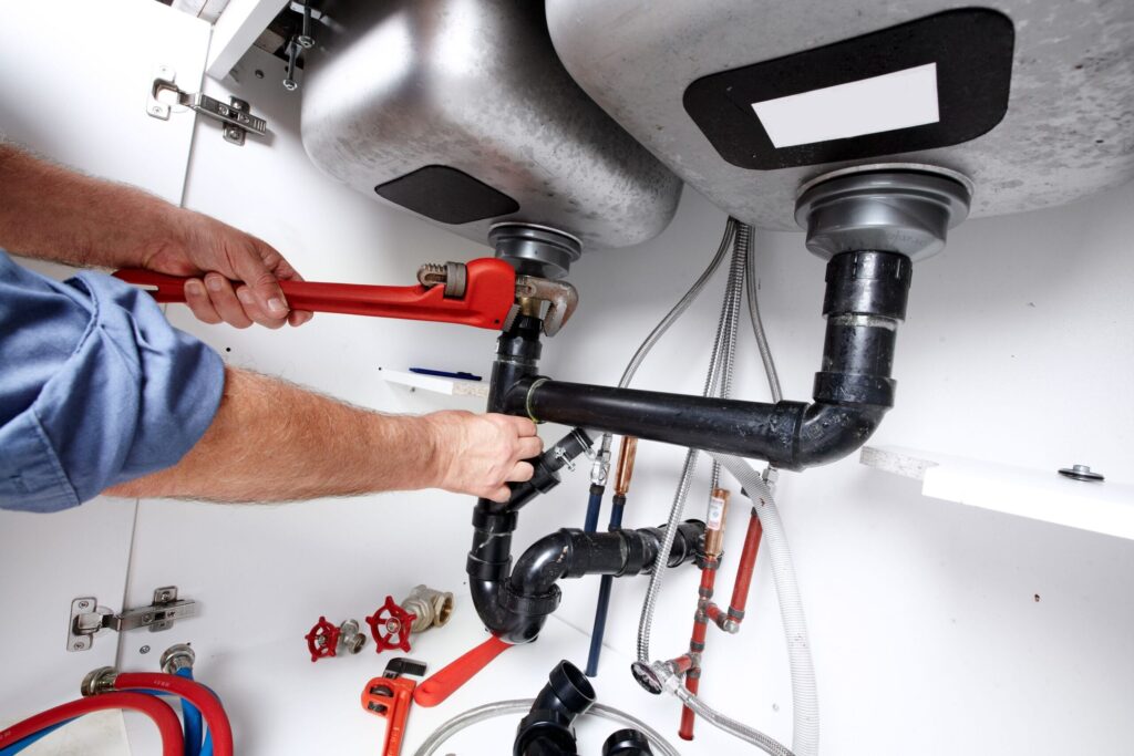 Plumber repairing drain pipes beneath a kitchen sink in Oviedo