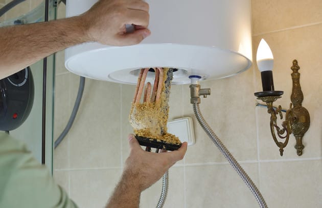 Technician removing mineral buildup from a water heater in Oviedo