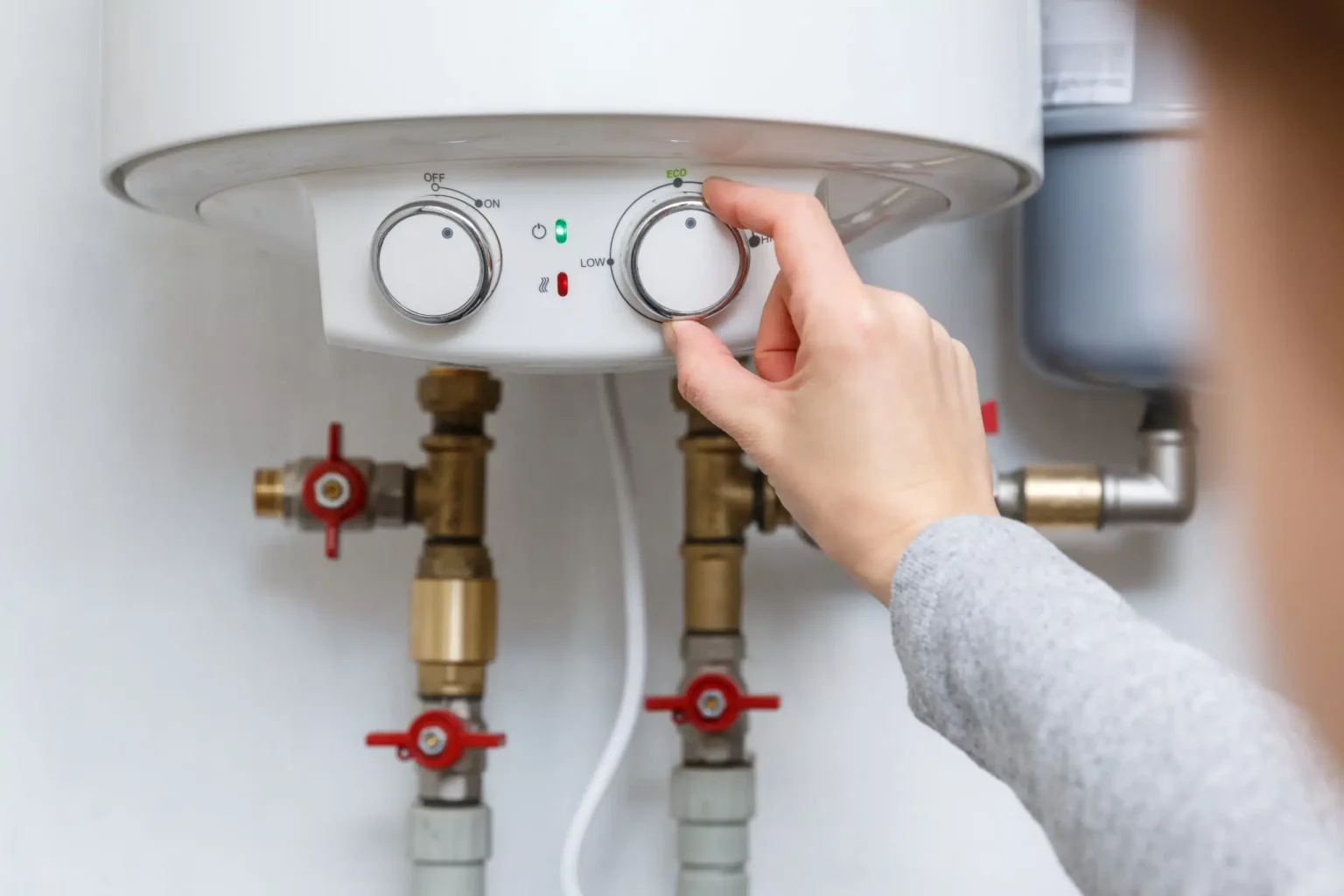Homeowner adjusting the temperature controls on a water heater in Oviedo